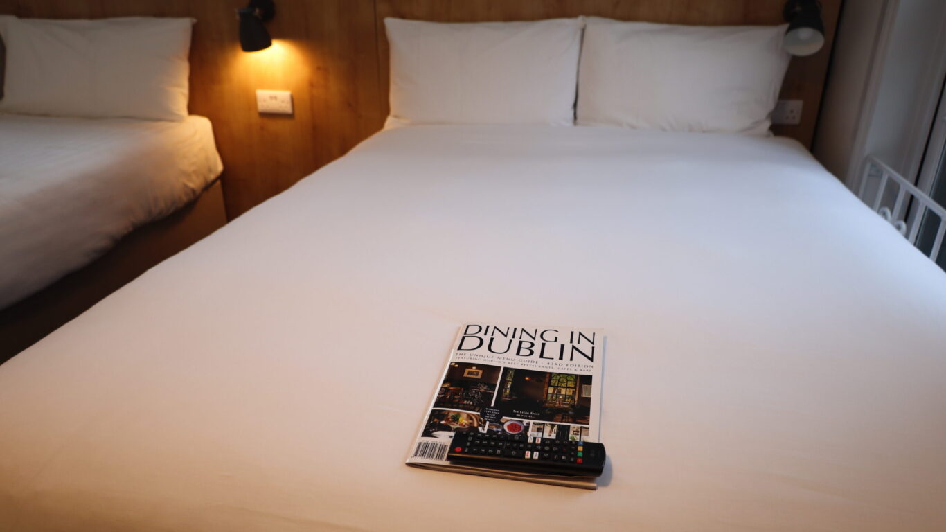 A neatly made hotel bed with white linens features a 