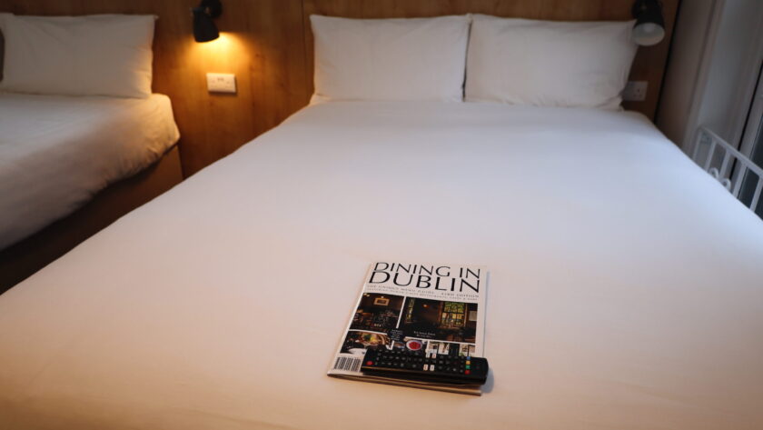 A neatly made hotel bed with white linens features a 