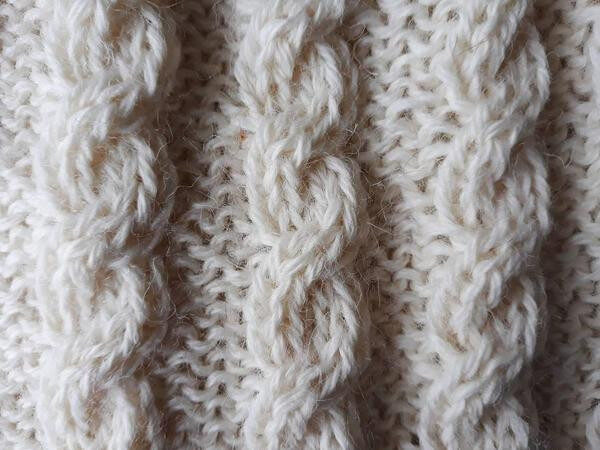 Close-up of a cream-colored knitted fabric with a cable knit pattern, showing thick, intertwined yarn strands&mdash;reminiscent of the cozy sweaters you&rsquo;ll find among unique things to do in Dublin.