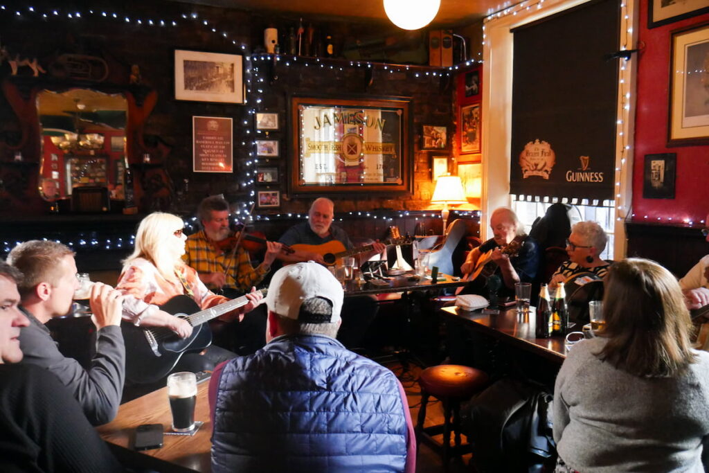 Guests enjoy live music and cosy atmosphere at the hotel pub, featuring traditional decor and warm lighting.