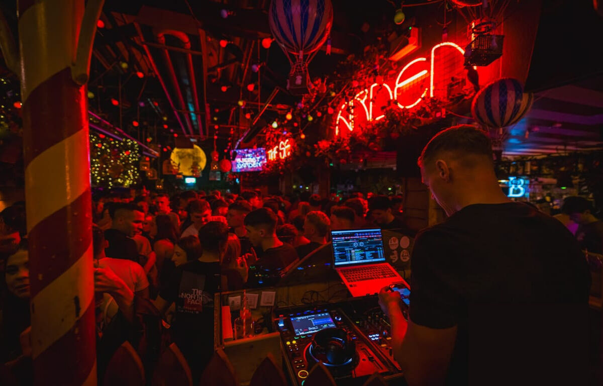 Vibrant hotel nightclub with lively crowd, neon lights, and DJ setting an exciting party atmosphere.