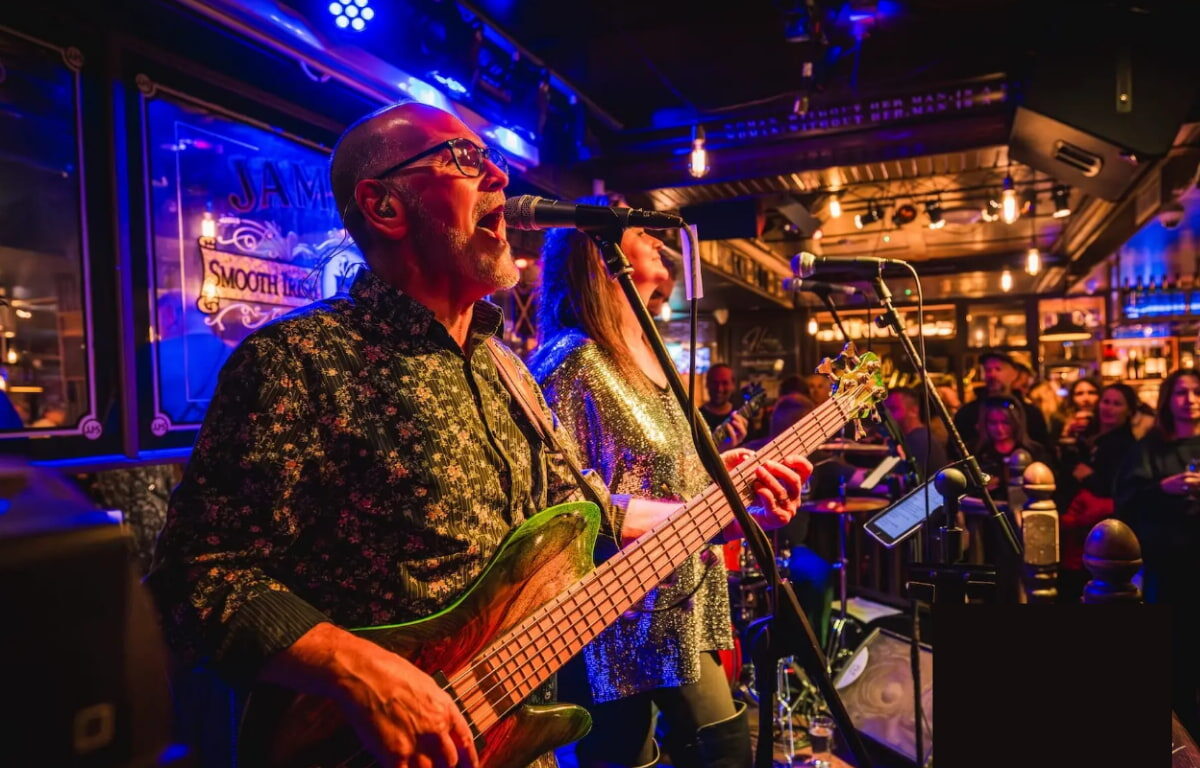 Energetic live band performance at hotel bar, vibrant lights, lively crowd, enjoying music and cocktails.