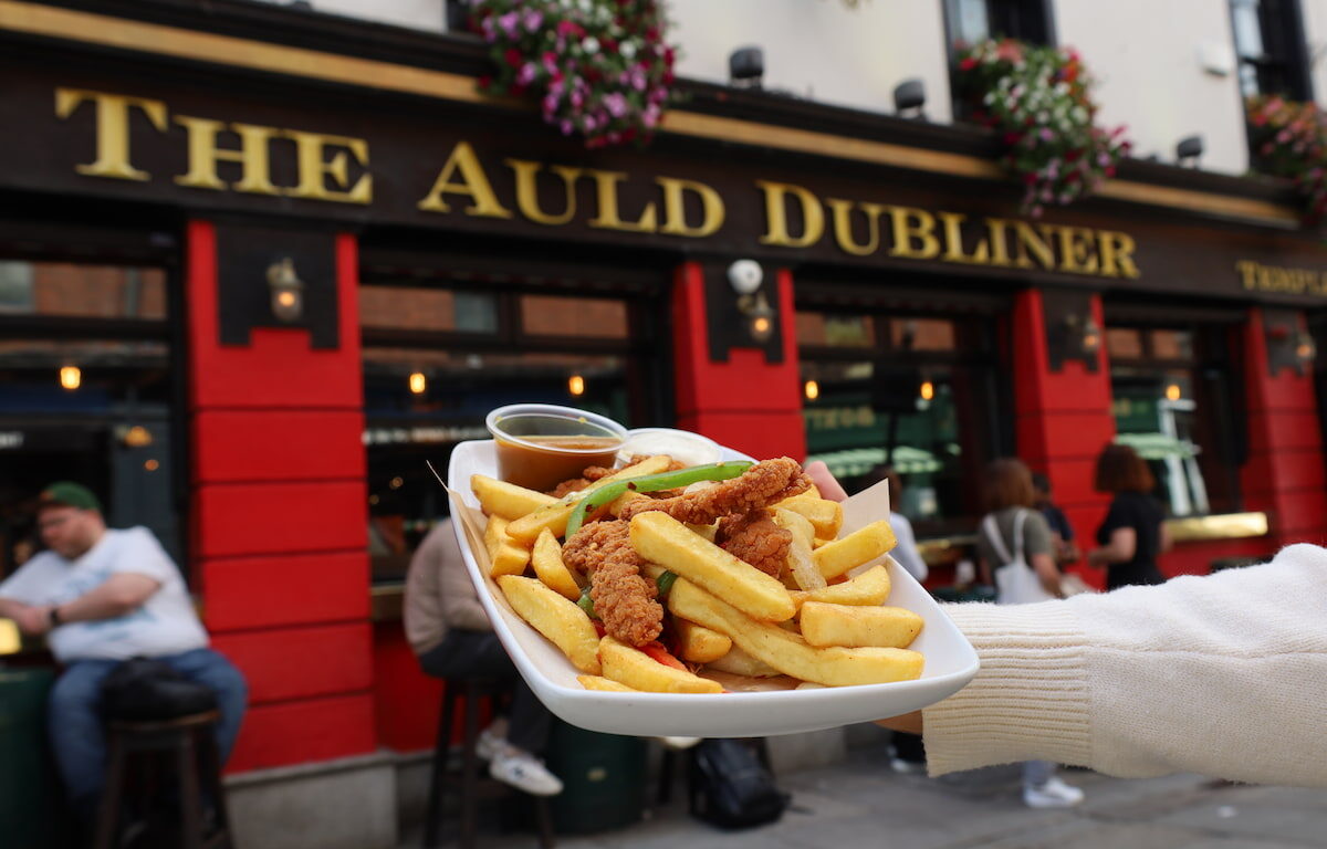 Delicious pub meal with fries and chicken outside The Auld Dubliner, showcasing vibrant Dublin street dining vibe.